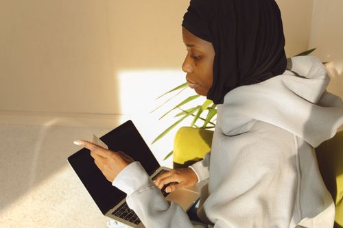 Free A woman in a hijab using a laptop for online shopping in a cozy indoor setting. Stock Photo