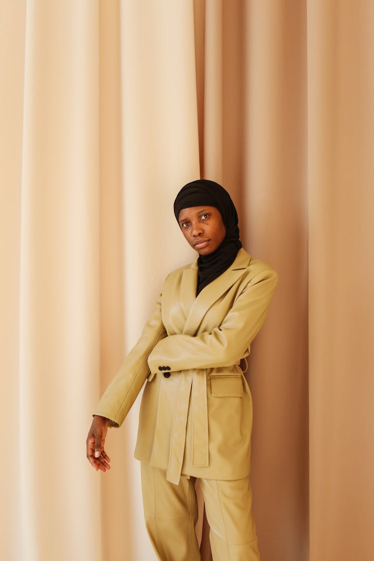 A Woman In Yellow Suit Standing Beside The Curtain