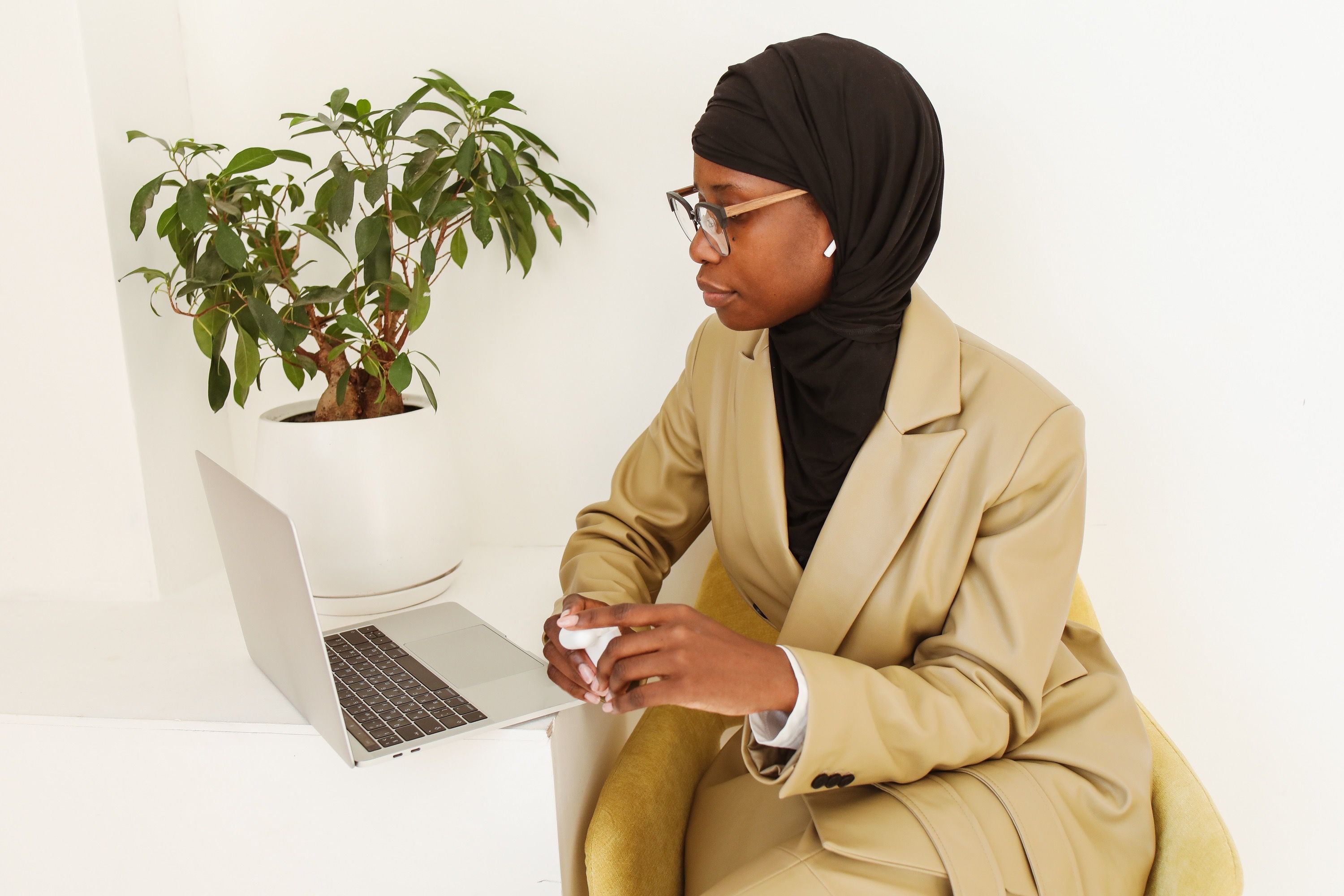 A Woman in Brown Coat Wearing Black Hijab Sitting Near a Laptop · Free ...
