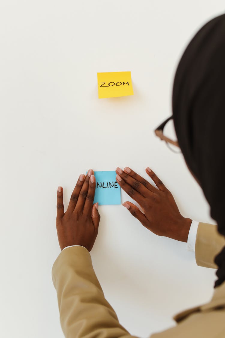 A Person Posting Sticky Notes On White Wall