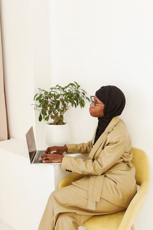 Photo of Woman Sitting on Chair While Using a Laptop