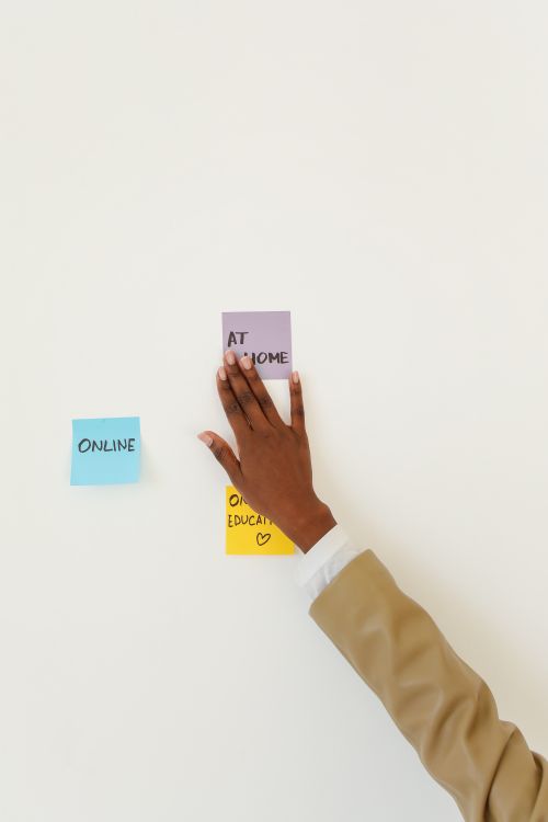 Free Close-up of a hand arranging sticky notes on a white wall for online education. Stock Photo