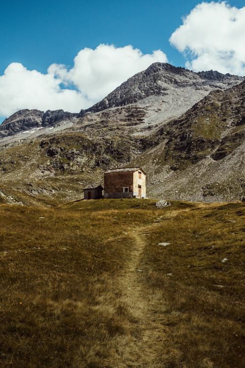 Free A solitary house nestled in the mountainous landscape of Chiavenna, Italy under a bright sky. Stock Photo