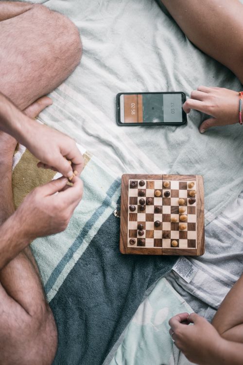 Free A casual chess game on a blanket with a smartphone clock outdoors. Stock Photo