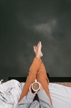 Top view of a person holding coffee, relaxing by water, early morning.