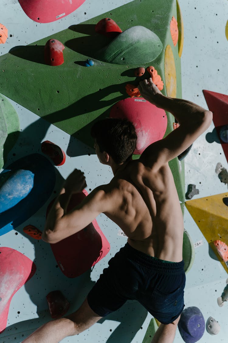 A Shirtless Man Bouldering A Wall