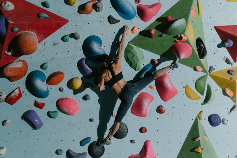 Climber mid-move on a colourful bouldering wall