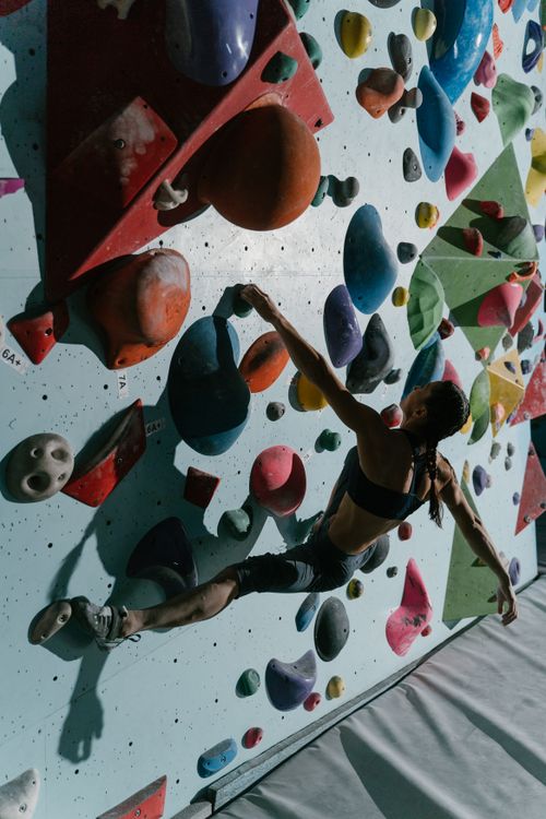 Free Woman scaling colorful indoor climbing wall showcasing agility and strength. Stock Photo