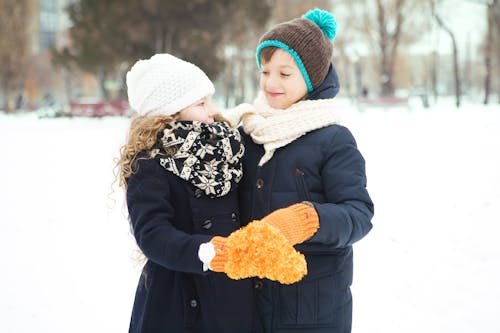 A Girl and a Boy in Winter Jackets Standing Close Together