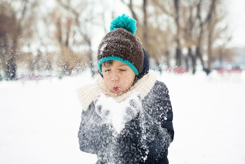 Free A Kid Blowing Snow from His Hand Stock Photo