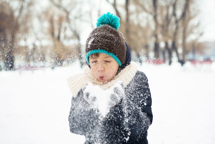 A Kid Blowing Snow From His Hand