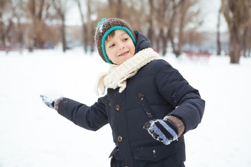 Free A happy child in a blue jacket playing with snow in a winter park. Stock Photo