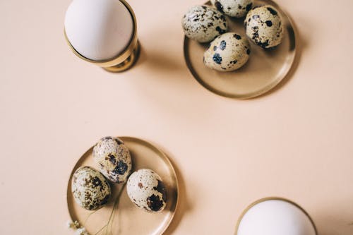 Quail Eggs on Brown Saucers Beside Chicken Eggs in Egg Cup
