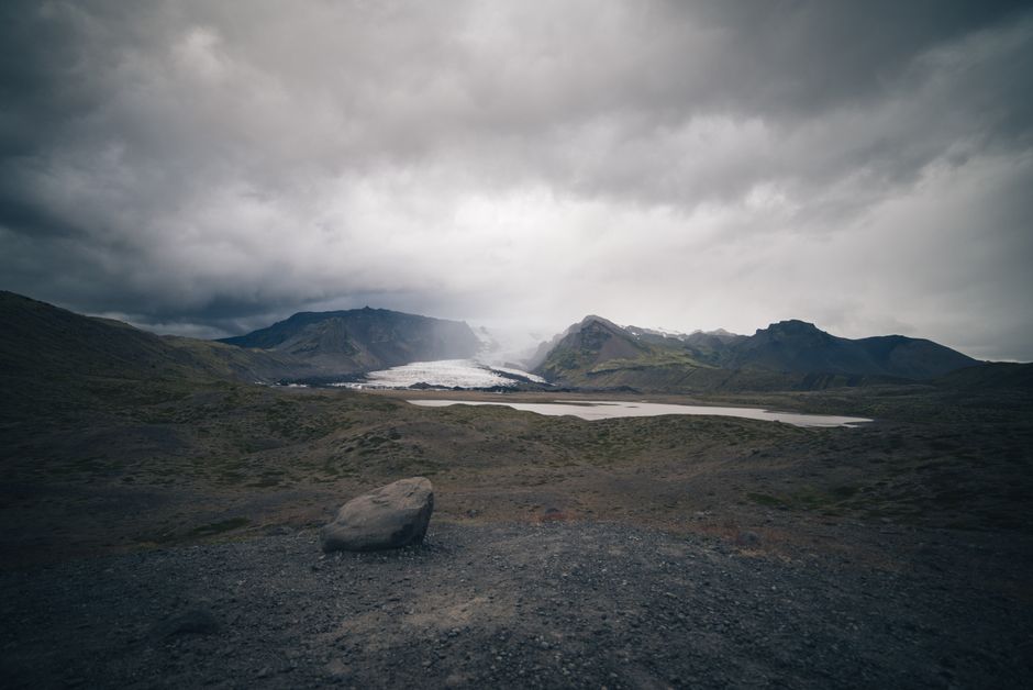 A breathtaking view of Iceland's rugged landscape featuring a glacier under a moody sky.