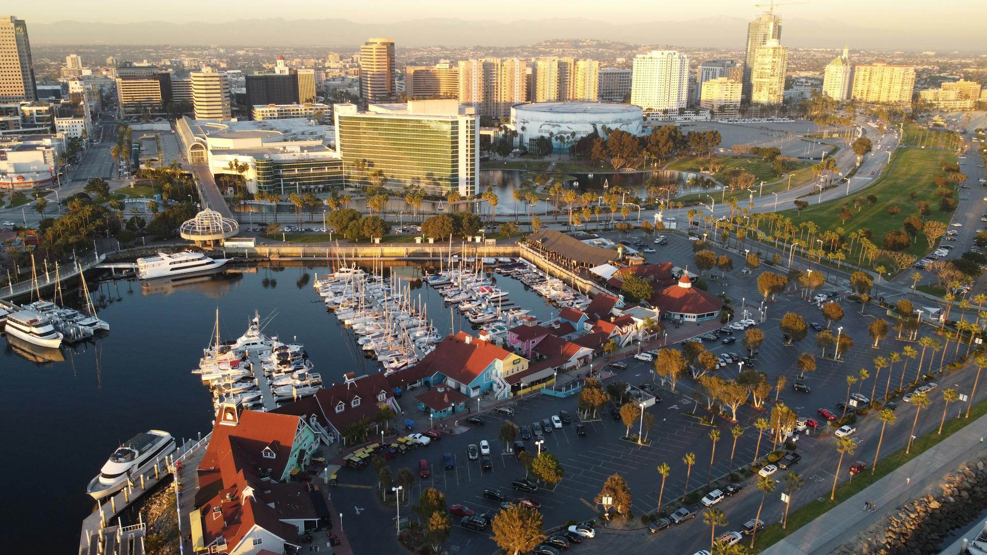 Stunning aerial shot of Long Beach Marina showcasing yachts, waterfront, and city skyline during sunset.