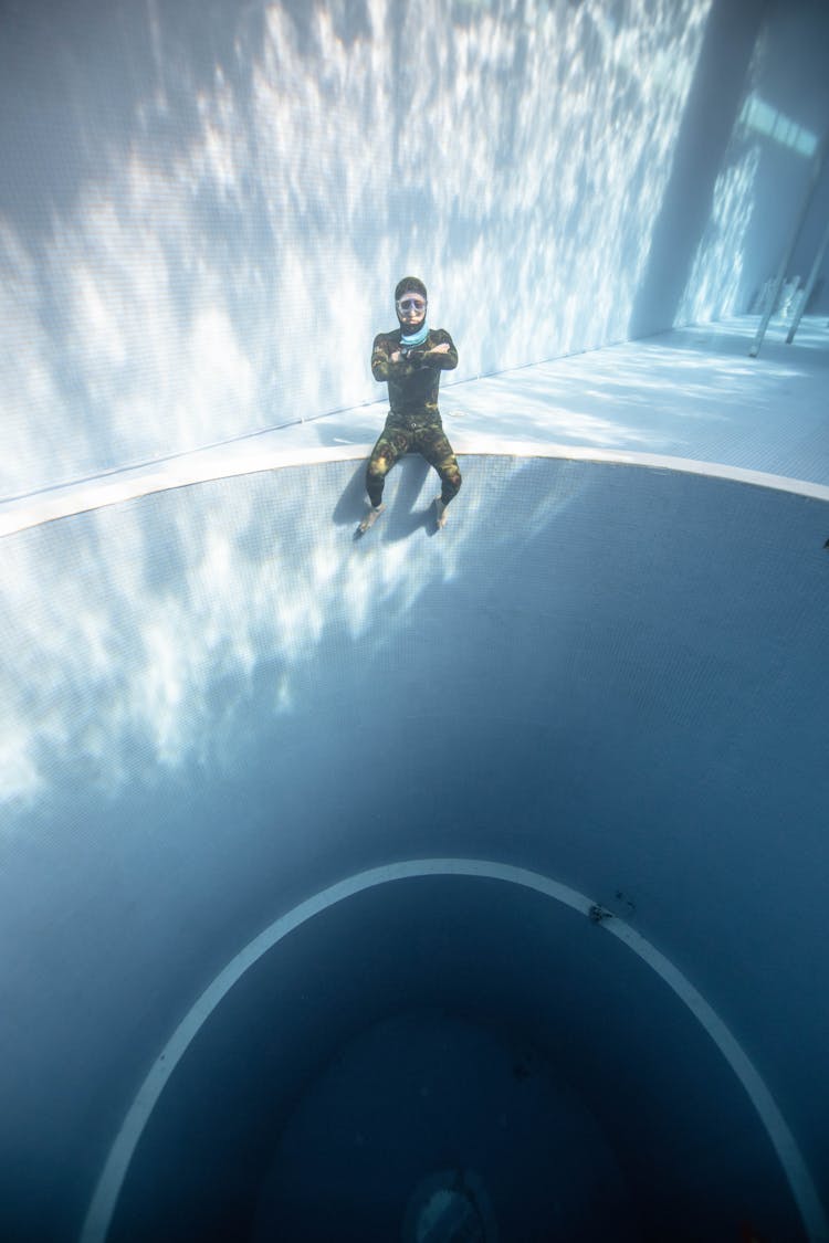 Lady Sitting On Round Hole Underwater In Pool