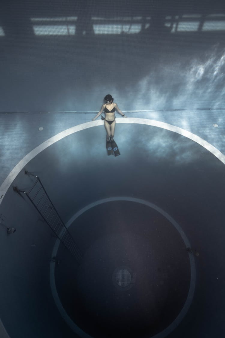 Faceless Woman Sitting In Pool Near Round Hole