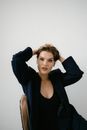 Woman in Black Blazer Sitting on Brown Chair