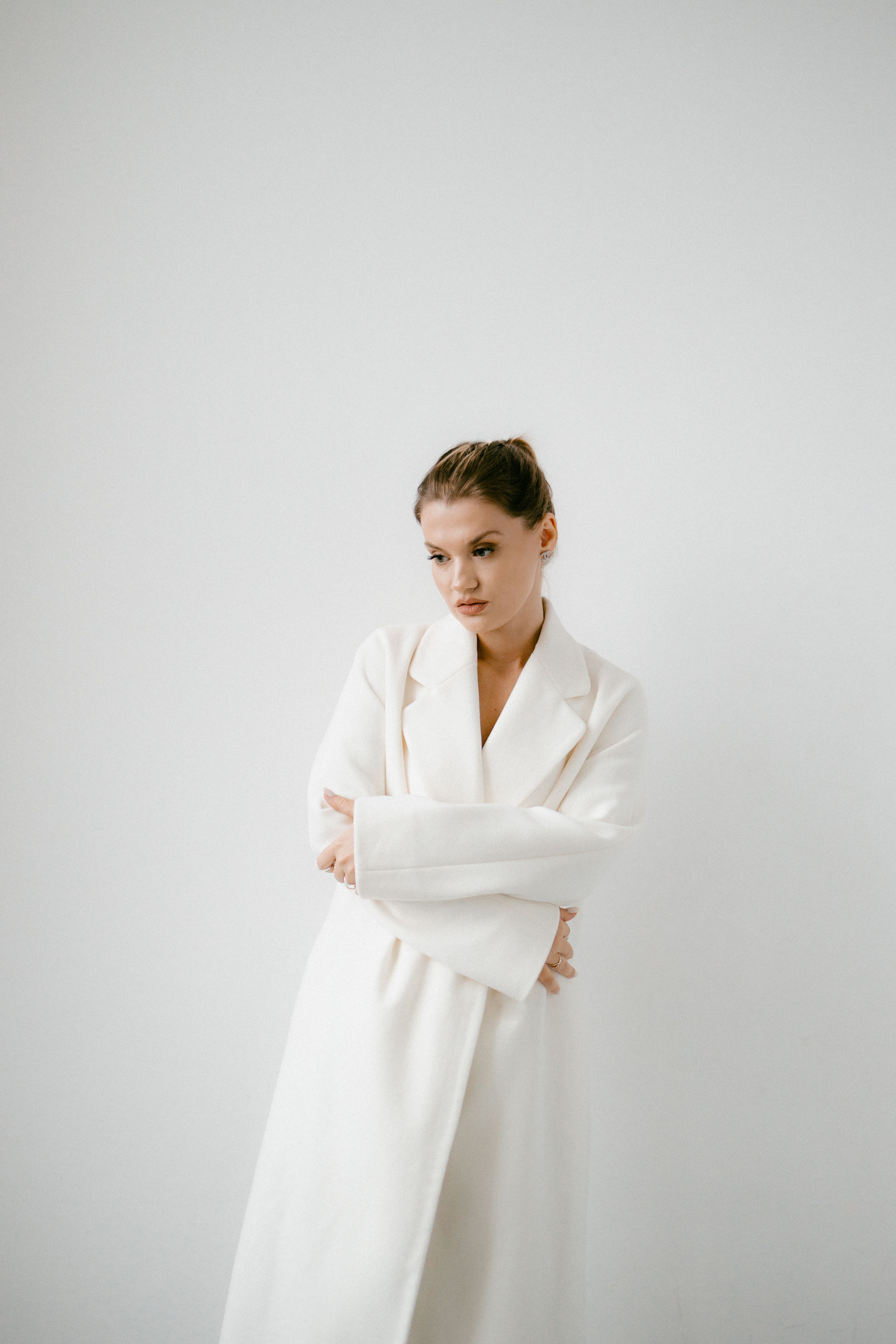 Woman in White Coat Near White Wall · Free Stock Photo