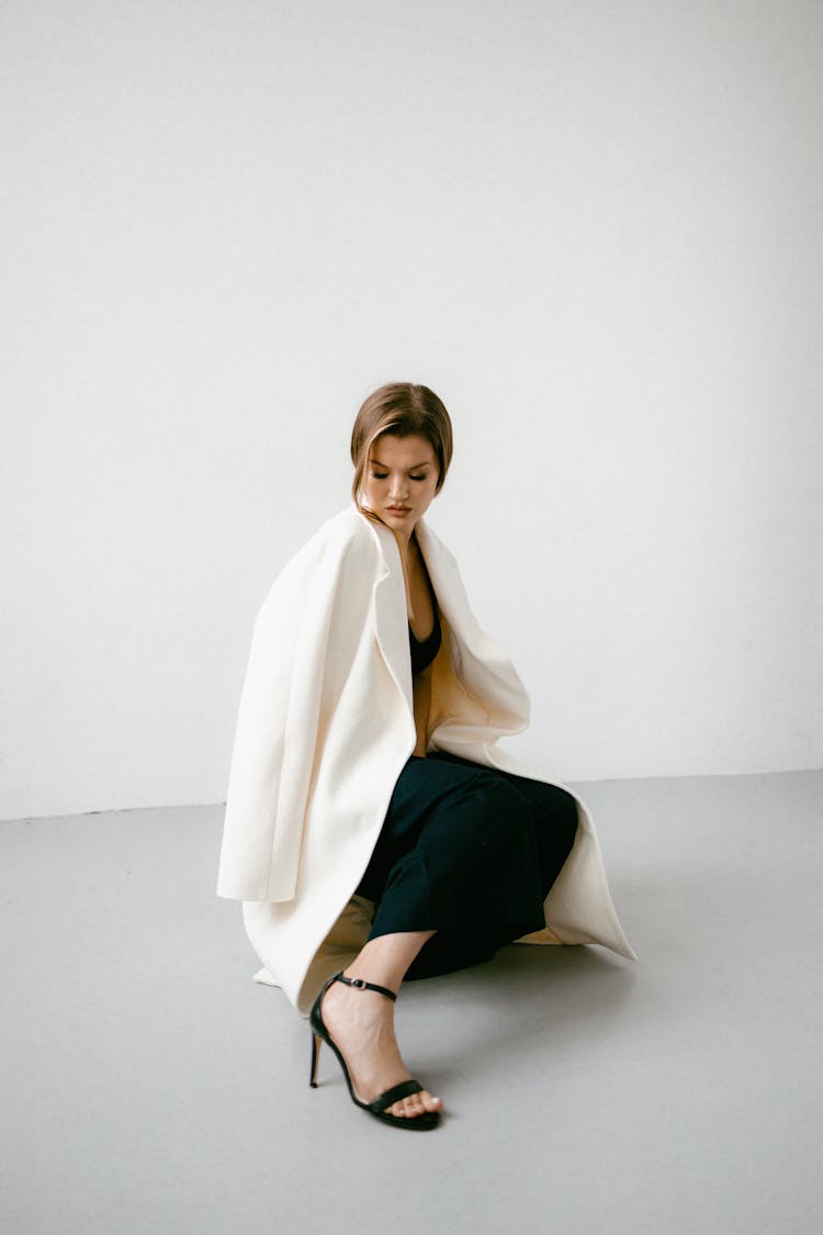 Pretty Woman In White Coat Squatting On Floor