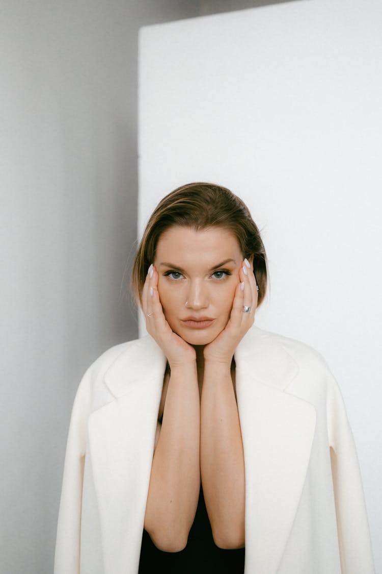 A Woman In White Blazer With Her Hands On Her Face