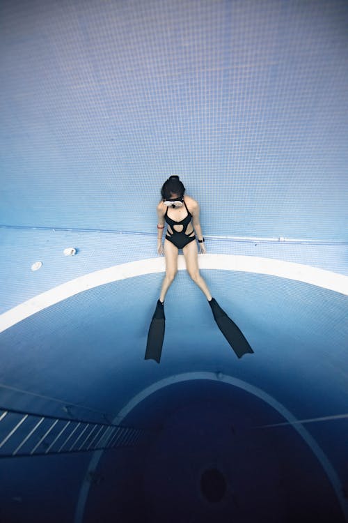 Female in diving mask and fins swimming in pool