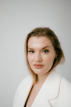 Close-up portrait of a woman in a white coat with a soft background, exuding elegance.