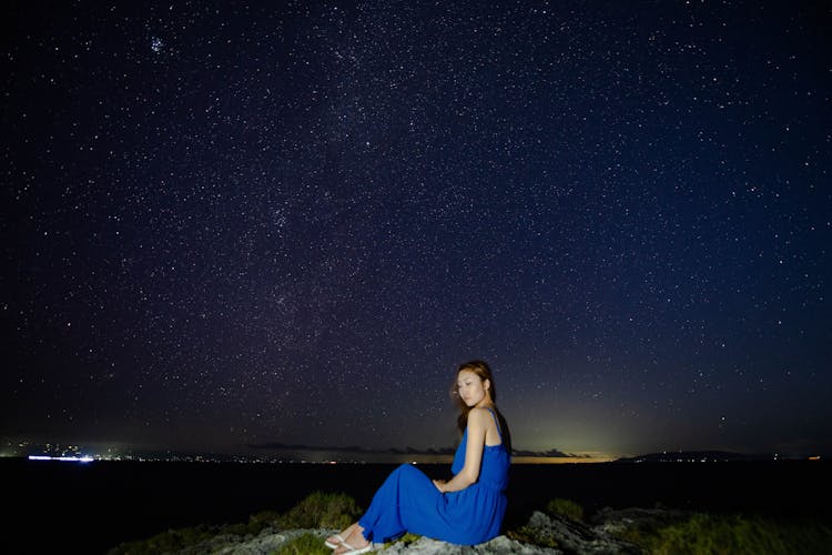 Asian Woman On Rocky Ground Under Starry Sky At Night