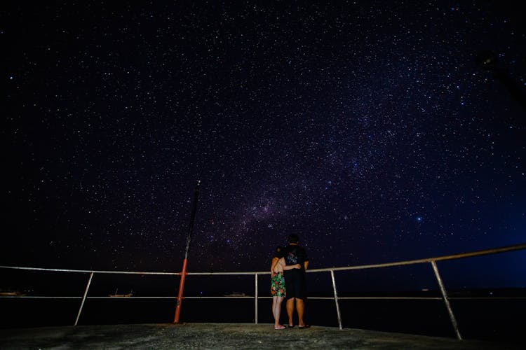 Faceless Couple On Observation Platform Admiring Starry Sky At Night