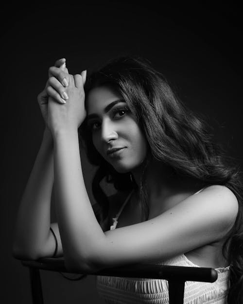 A Grayscale Photo of a Woman in White Tank Top with Her Hands Together