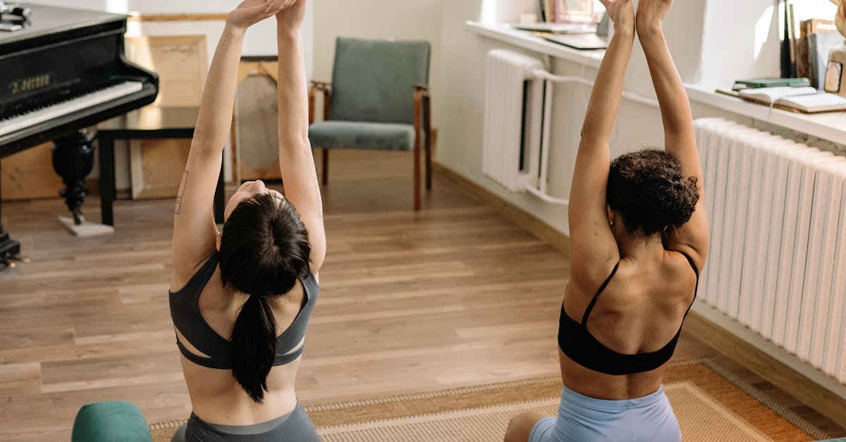 Two women in sportswear performing yoga in a cozy living room.