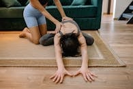 Woman in Blue Tank Top and Black Shorts Doing Yoga on Brown Wooden Floor