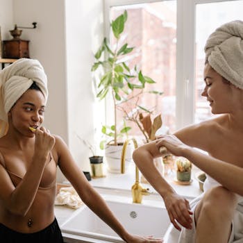 Two women engaging in self-care activities with towels on their heads in a cozy bathroom setting.