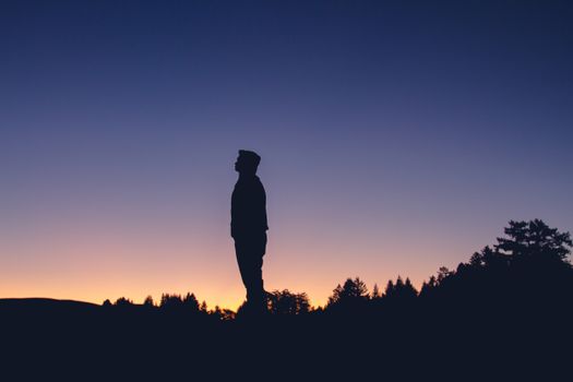 一个孤独的身影在五彩斑斓的日落天空下，以剪影的姿态唤起孤独与反省