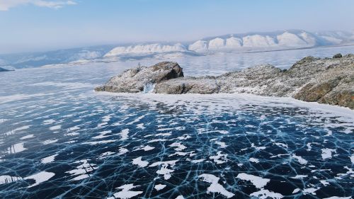 Free Breathtaking aerial shot of Lake Baikal's frozen surface, showcasing intricate ice patterns and snow-covered rock formations. Stock Photo