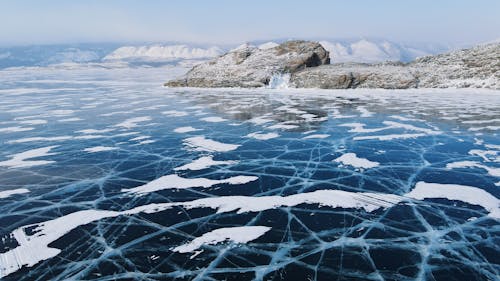 Frozen Body of Water With Cracks Near Rocky Mountains