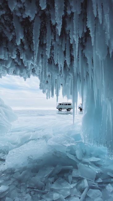 Van parked on icy Lake Baikal, Irkutsk Oblast, Russia, beneath frozen icicles.
