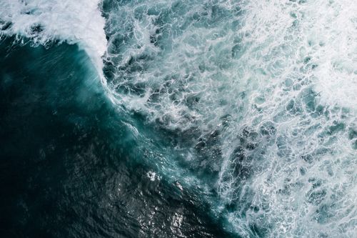 Free A captivating aerial shot capturing the dynamic movement of ocean waves crashing against each other, emphasizing nature's power. Stock Photo