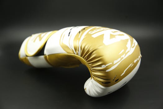 Vibrant gold boxing glove close-up on black background, highlighting its sleek design.