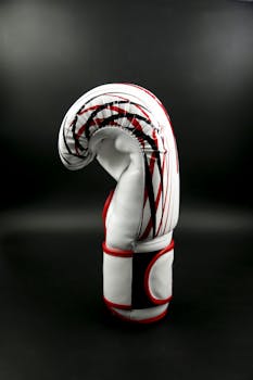 Detailed side view of a single red and white boxing glove on a black background.