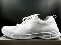 White leather trainer photographed in profile against a dark studio wall — photo by Montage Art Media on Pexels