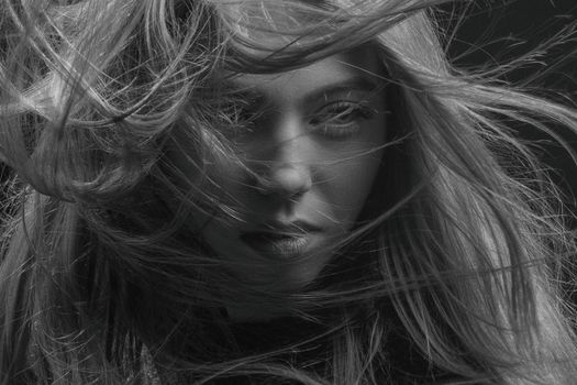 Striking black and white close-up portrait capturing the intense gaze of a woman with flowing hair.