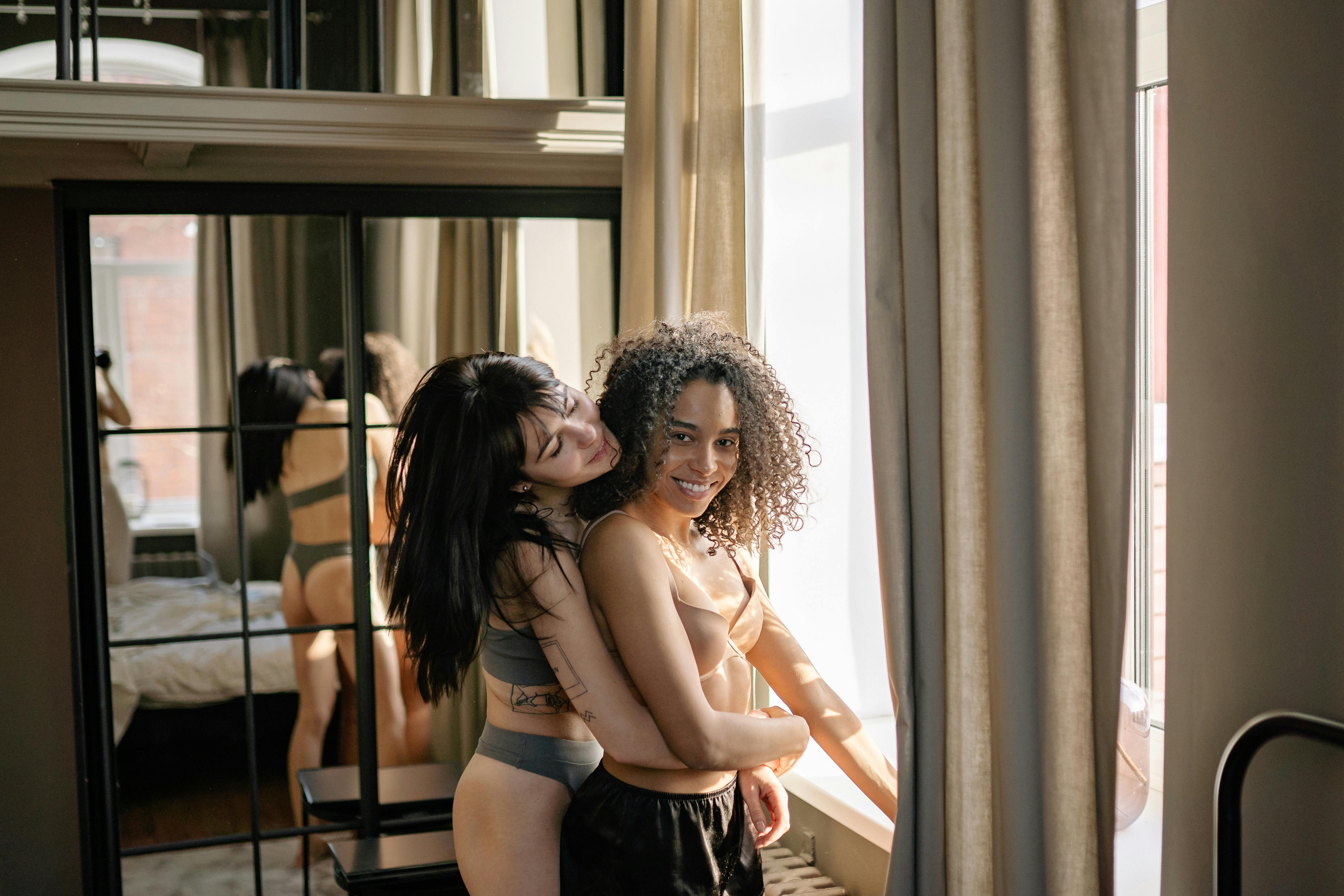 woman in black and white floral bikini top and blue denim daisy dukes standing near window