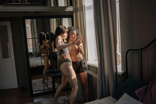 Free A young couple enjoying a tender moment indoors by a window, lit by soft sunlight. Stock Photo
