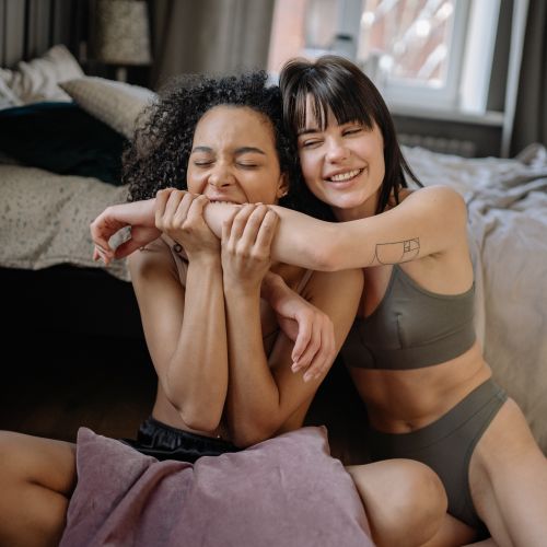 Free A happy interracial couple laughing and embracing in a cozy bedroom setting. Stock Photo