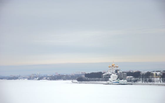 A serene winter landscape featuring an Orthodox church with golden domes beside a frozen river.