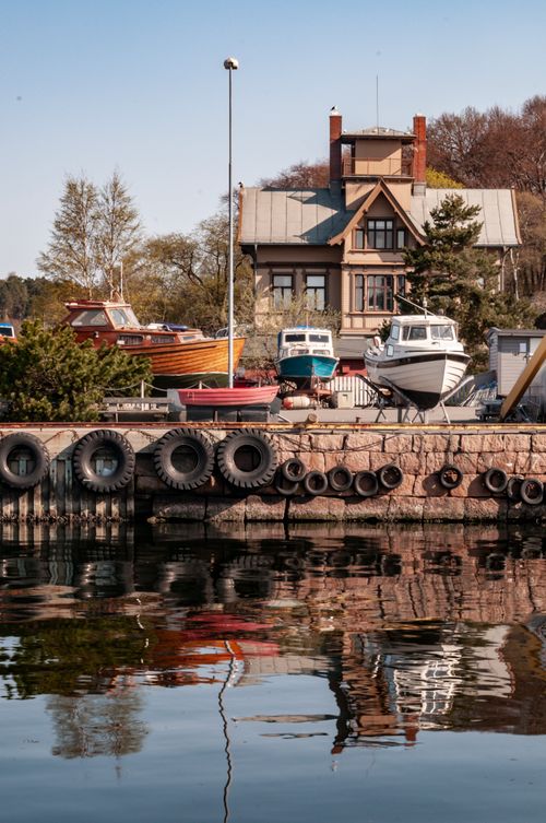 Free Beautiful waterfront view with boats and historic house reflecting in calm water Stock Photo