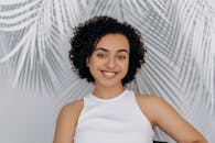 白色棕榈叶背景下一位卷发微笑的女人的肖像