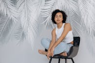 一位卷发时尚女性的肖像，以当代棕榈叶为背景，摆出轻松的姿势