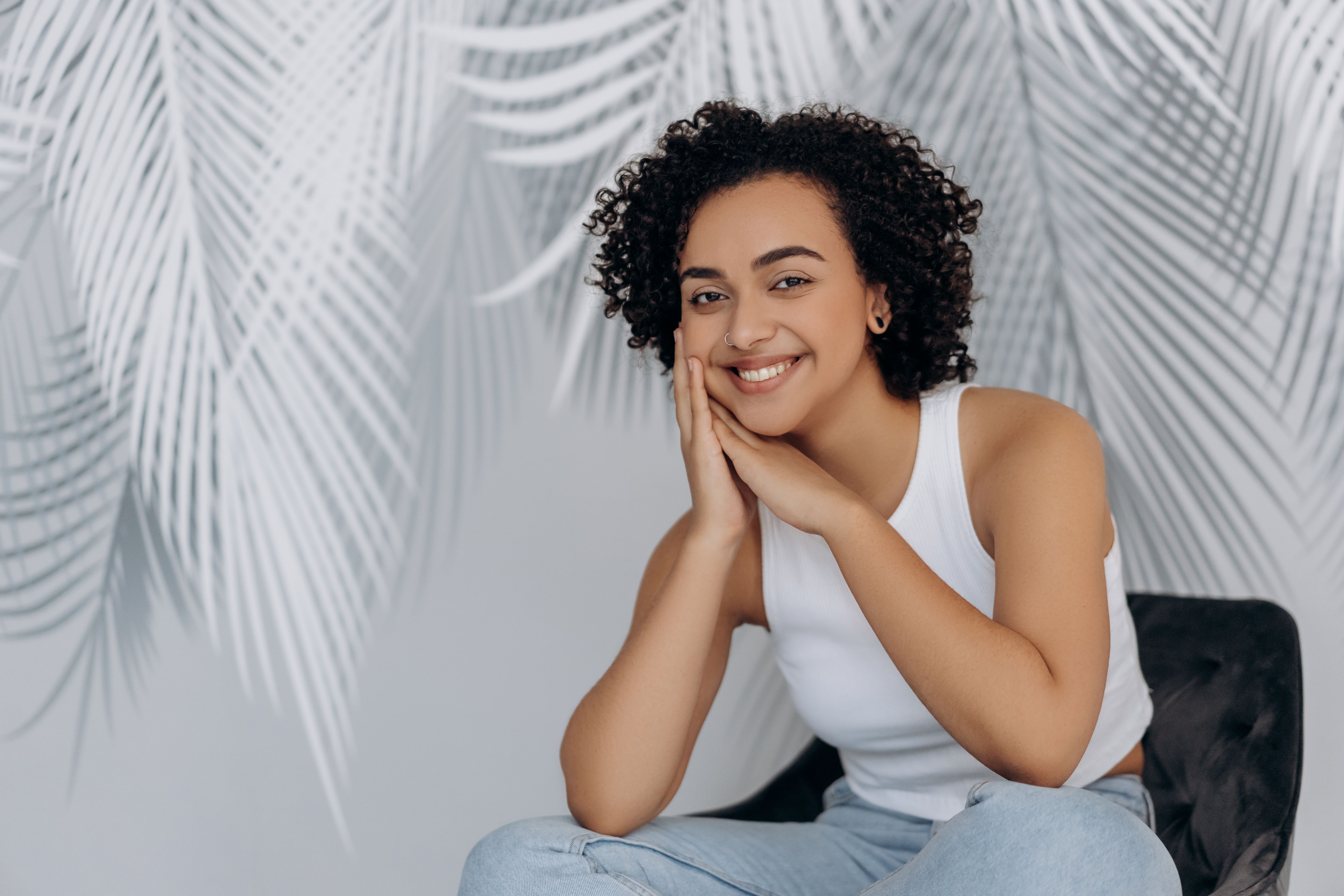 Woman in White Tank Top and Blue Denim Jeans Sitting on Black Chair ...
